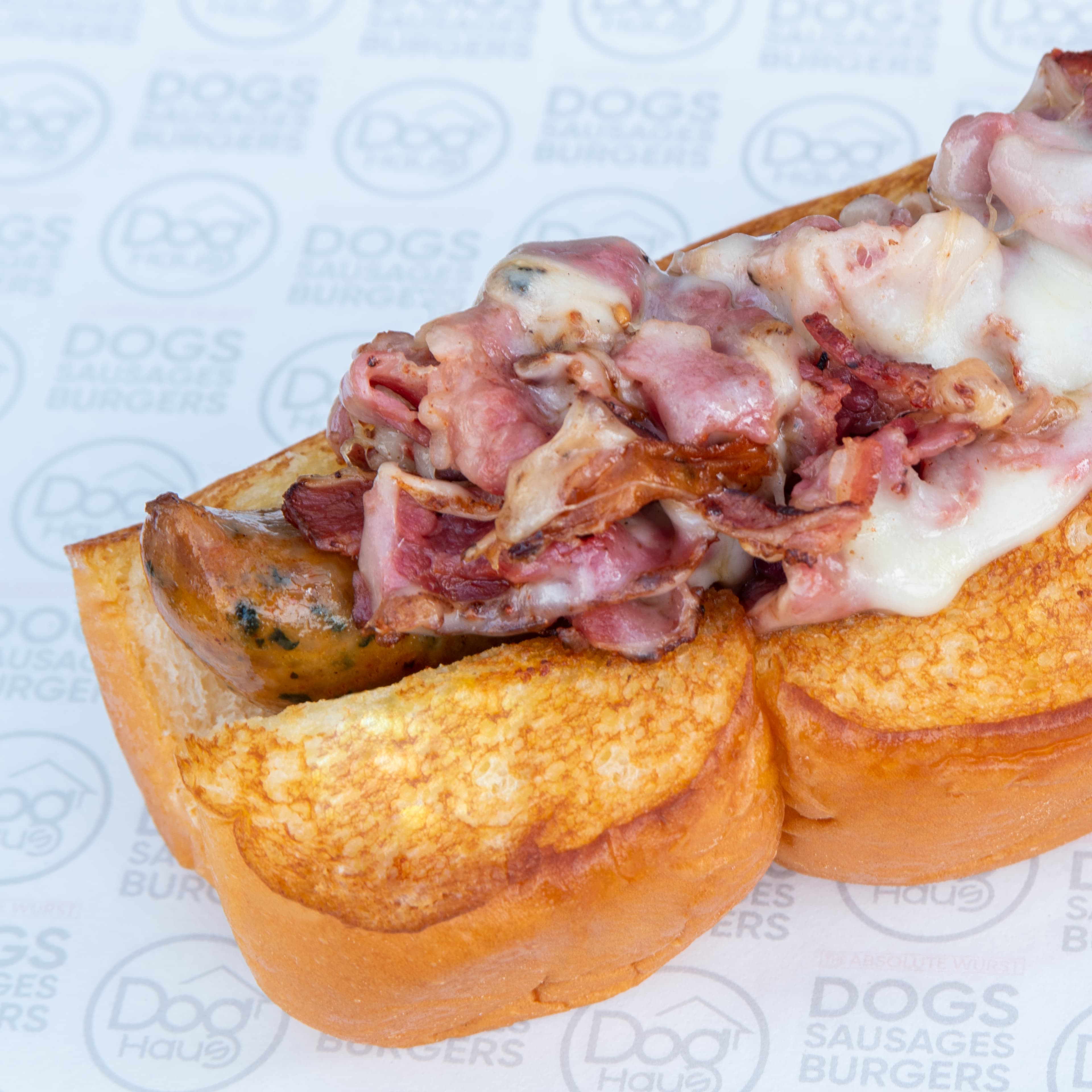 Sausage topped with melted cheese and pastrami on a bun