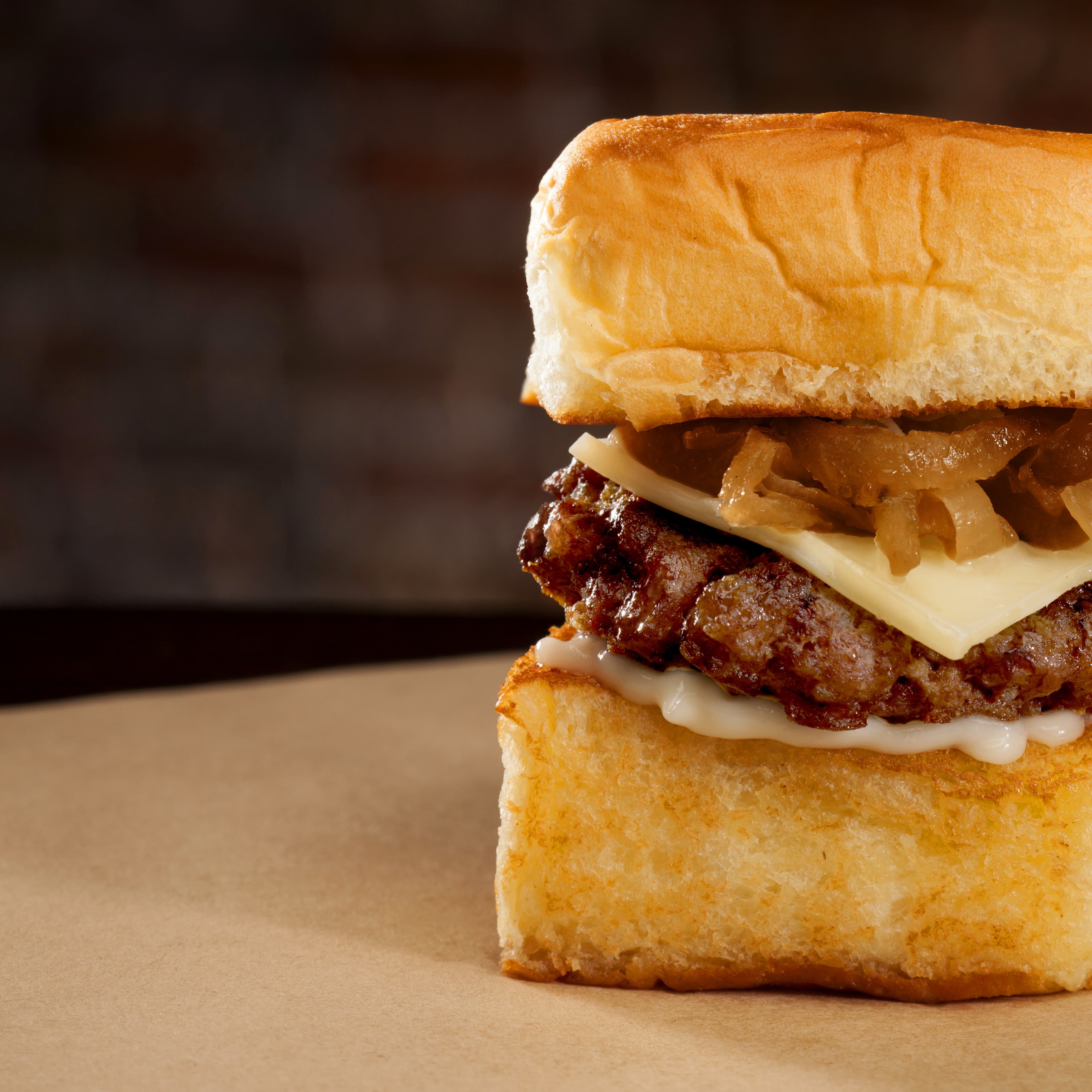 Slider with grilled onions, cheese, and beef patty on toasted bread