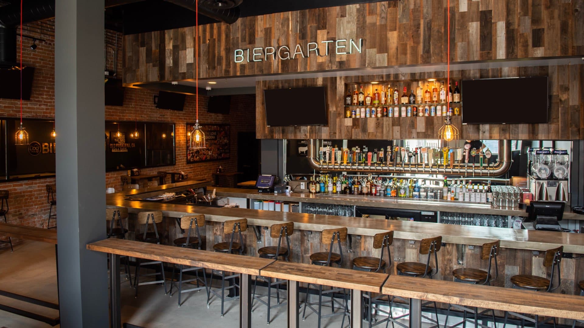 Dog Haus Old Pasadena bar interior with rustic wood paneling, neon “Biergarten” sign, and a long bar lined with industrial-style stools.