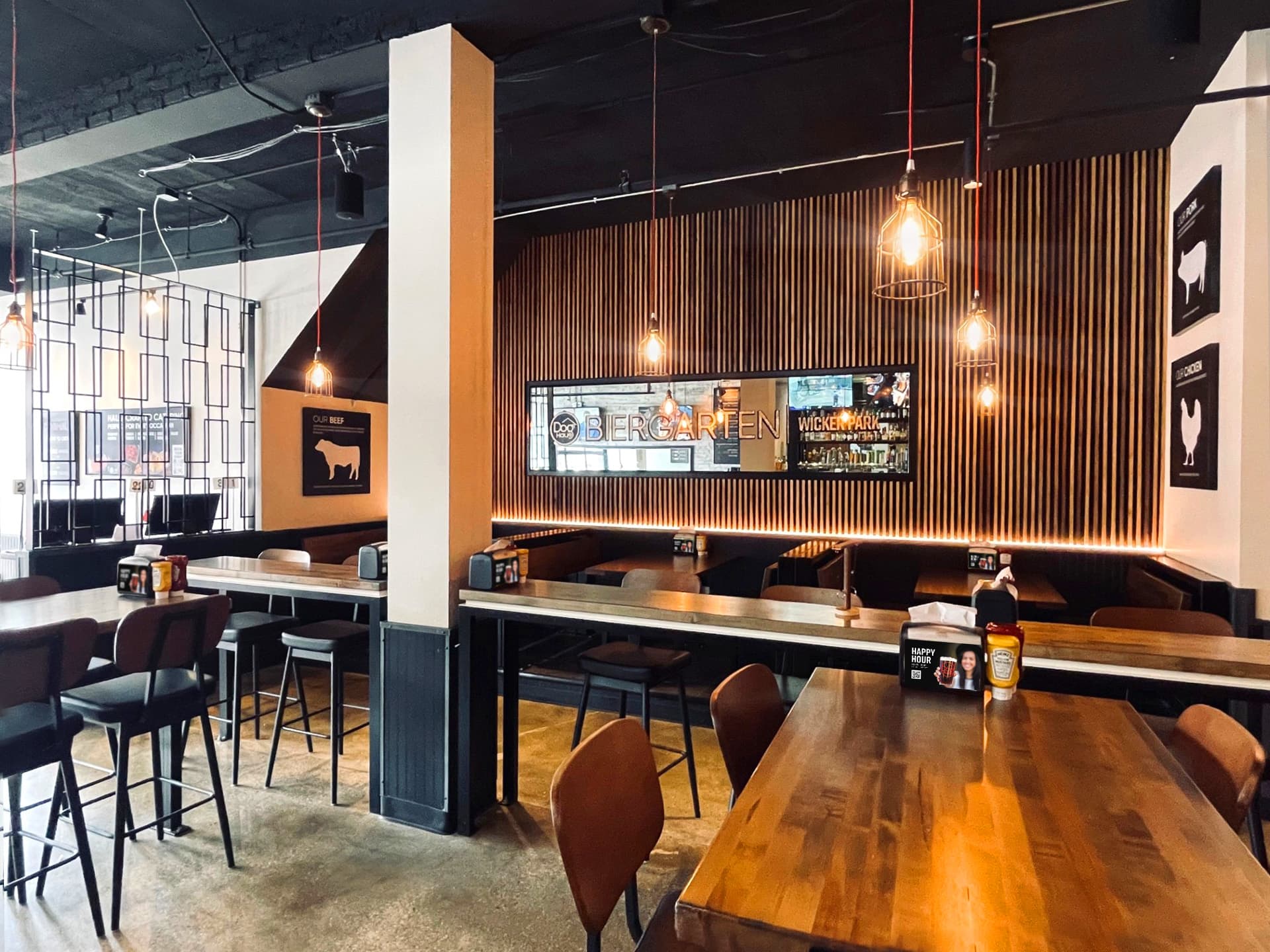 Interior view of Dog Haus Biergarten Wicker Park featuring booth seating, modern wood slat wall, and warm pendant lighting.
